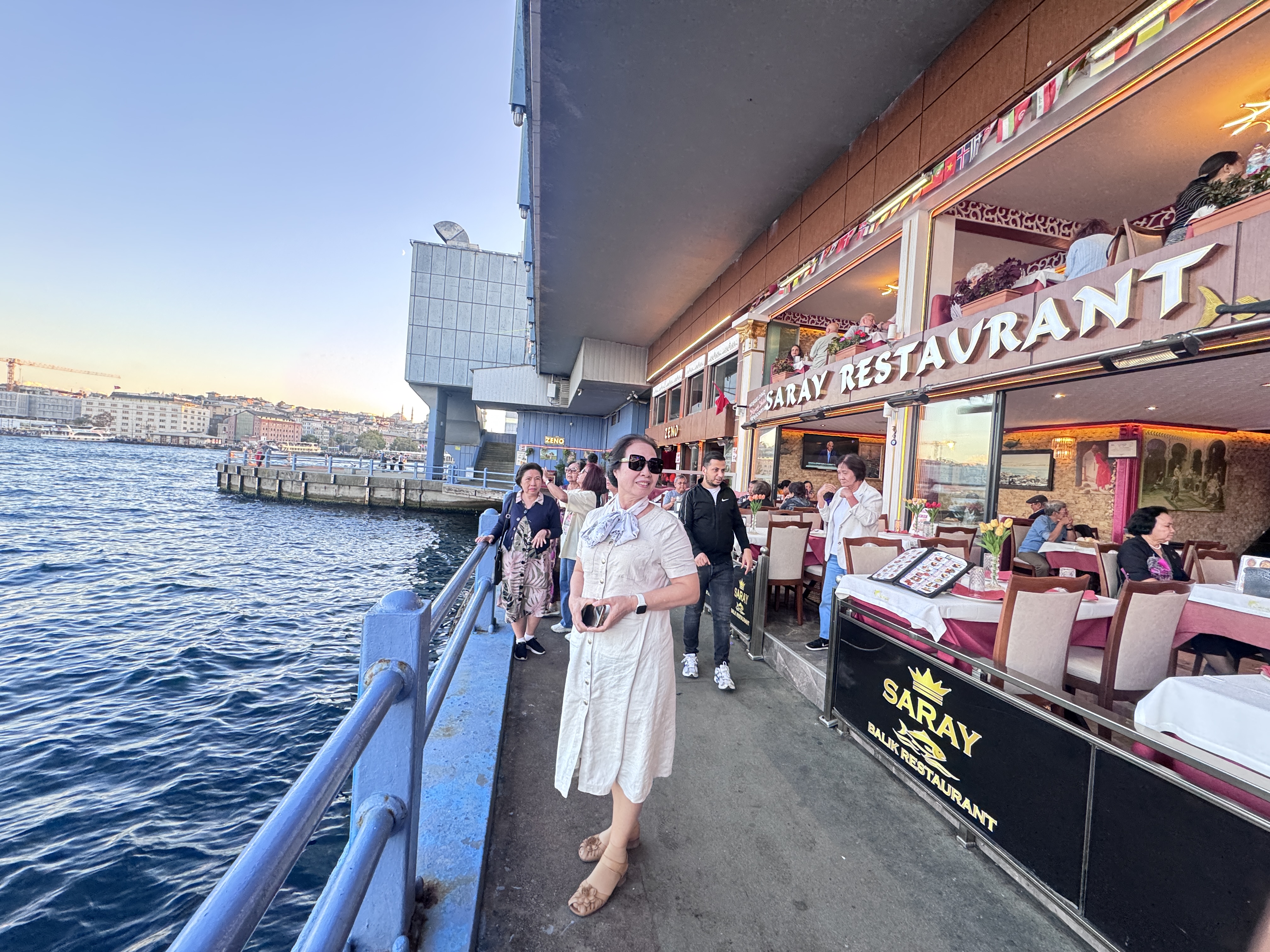 Khách đoàn trên lối ven nước cạnh dãy nhà hàng ở tầng dưới cầu Galata